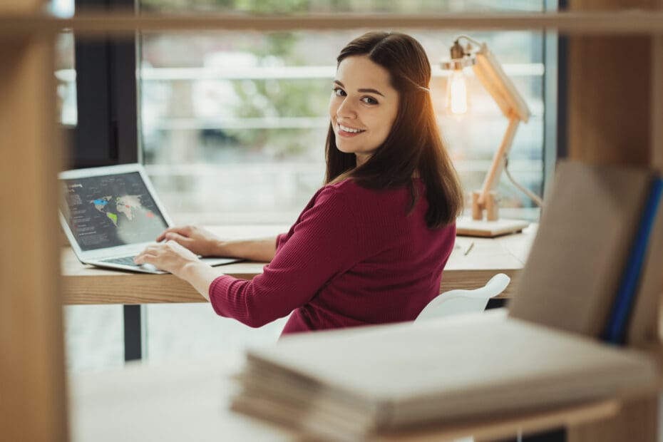 Smiling woman at desk with laptop ready to study business and develop essential skills