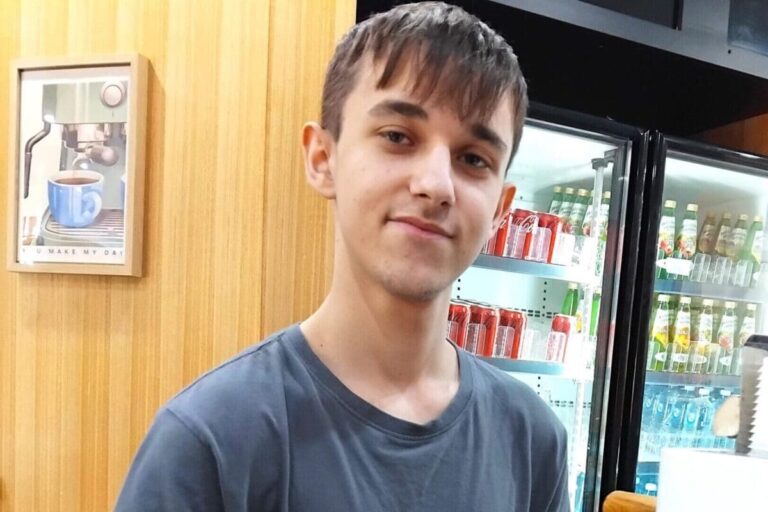 Cameron holding a milk jug while preparing coffee at a café coffee machine