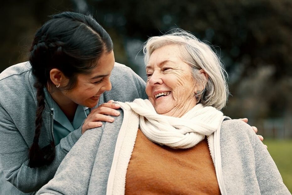 Caregiver helping woman with disability in park for support, trust and care in retirement. Nurse talking to happy senior patient in wheelchair for rehabilitation, therapy and conversation in garden