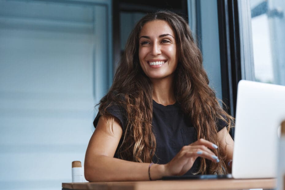Smiling professional woman working on a laptop in a modern workspace searching for business workforce training.