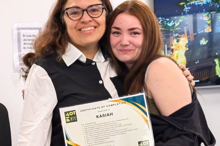 Kasiah smiles as she hugs her trainer Ellie while holding her Certificate I in Skills for Vocational Pathways, marking her achievement in the Skills for Education and Employment Program (SEE program) and her progress in learning for employment whilst exploring Australian career pathways.
