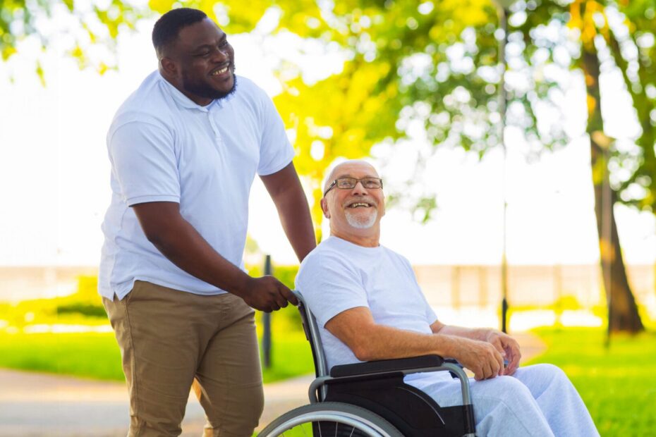 Person supporting an older adult using a wheelchair in an outdoor setting, representing a disability support worker role and learning for employment.