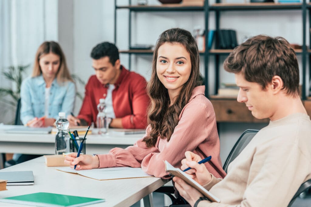 Learners seated in a classroom using notebooks and devices as a part of a blended learning approach
