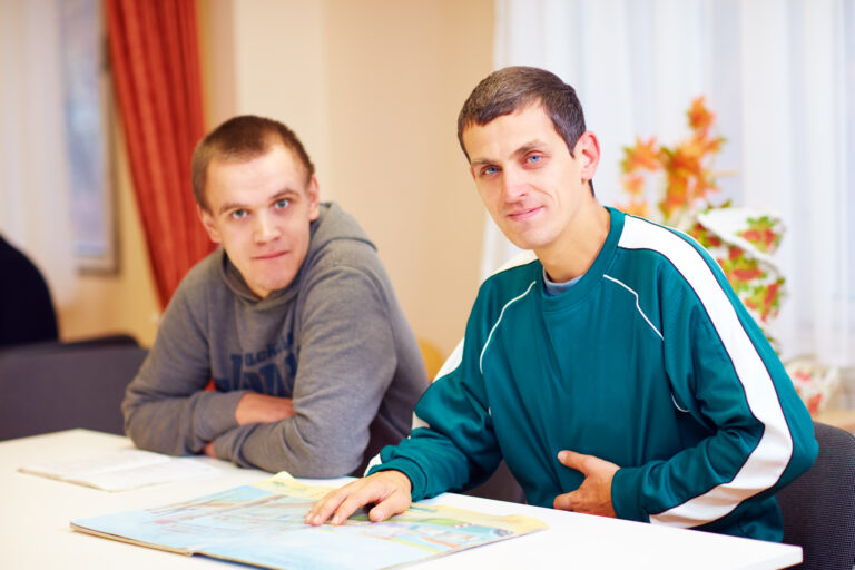 Two learners seated at a table reviewing learning materials, representing inclusive learning and reducing learning barriers in a supportive training environment.