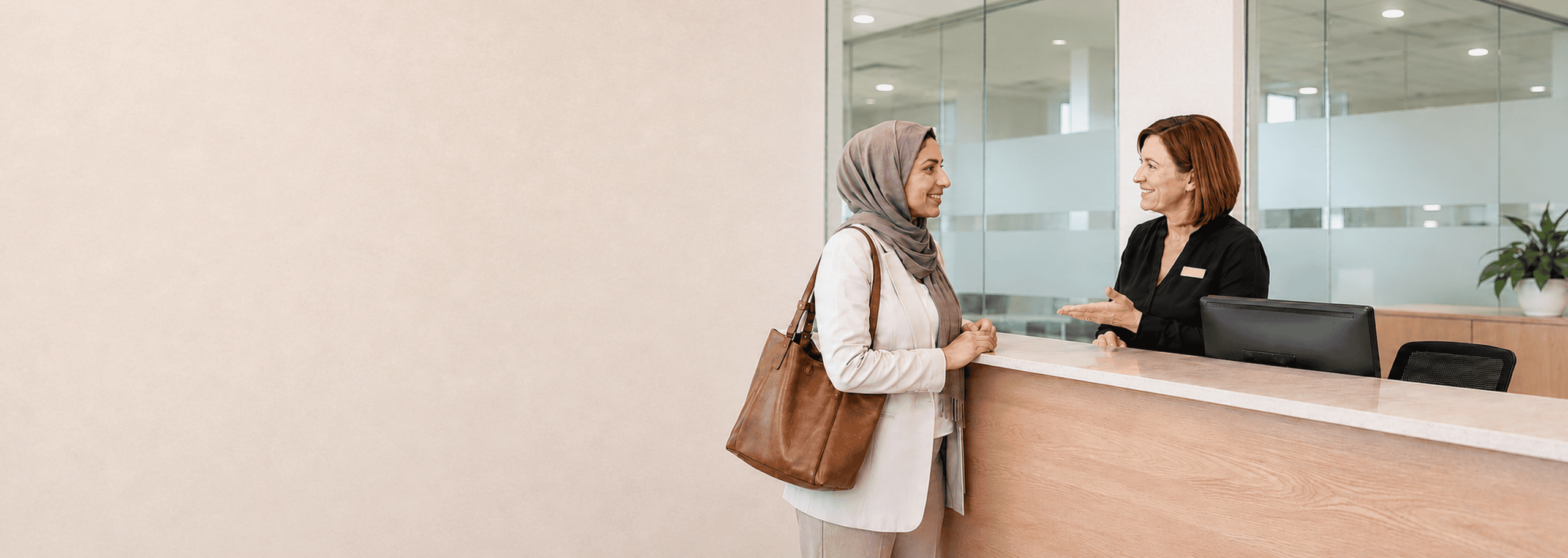 Person speaking with a staff member at a reception desk, representing confidence using English in everyday situations.